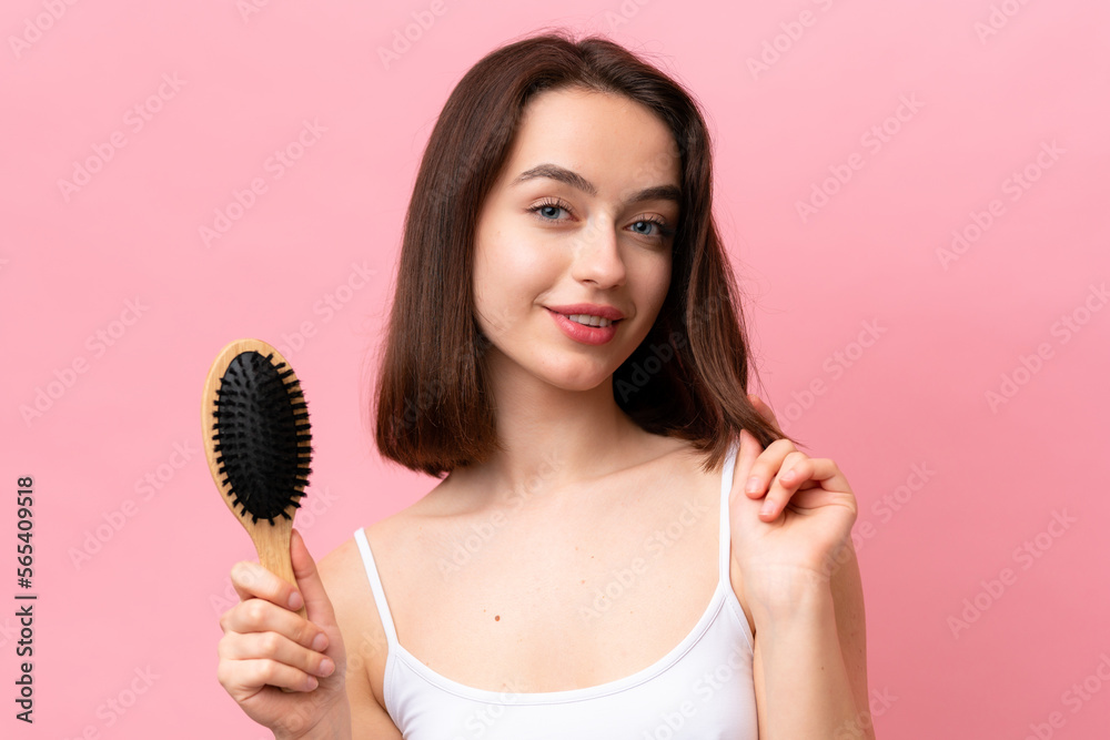Young Ukrainian woman isolated on pink background with hair comb Young Ukrainian woman isolated on pink background with hair comb