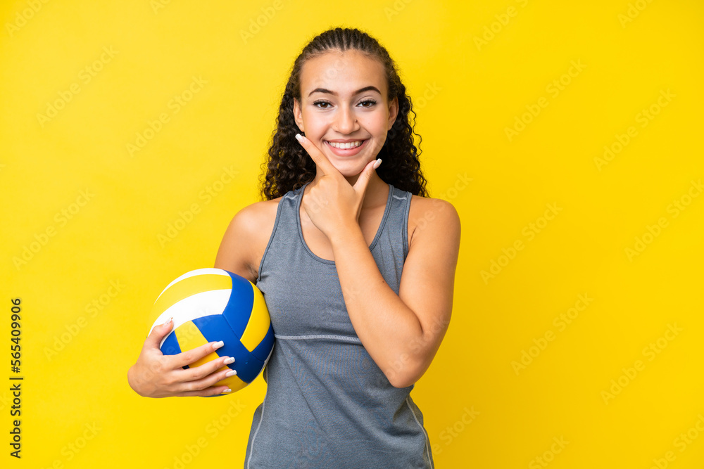 Young woman playing volleyball isolated on yellow background happy and smiling