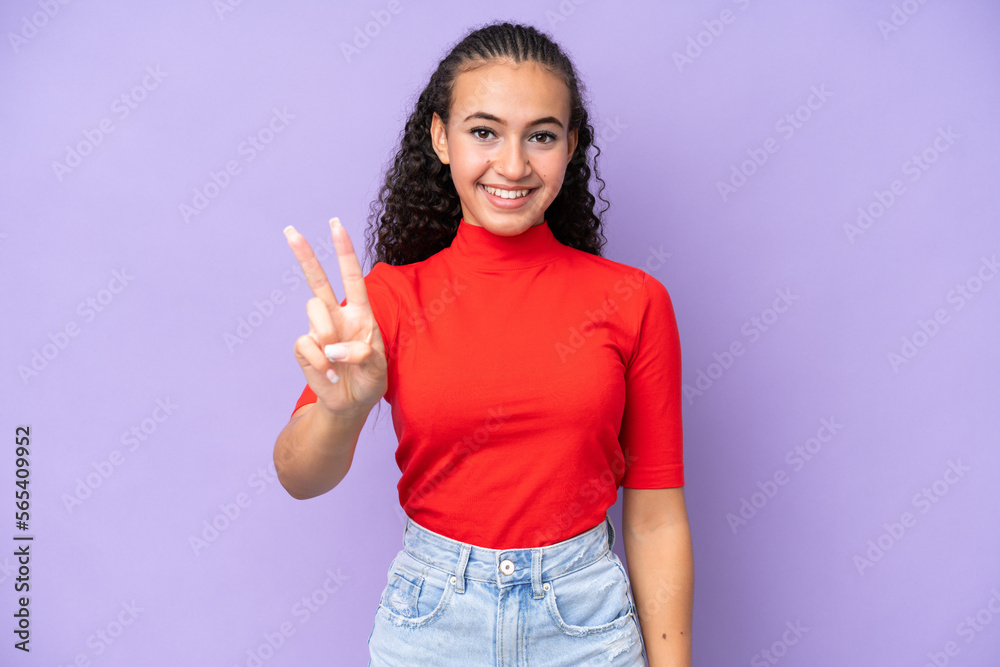 Young woman isolated on purple background smiling and showing victory sign Young woman isolated on purple background smiling and showing victory sign