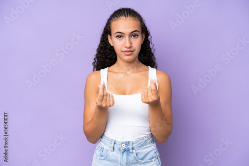 Young woman isolated on purple background making money gesture but is ruined