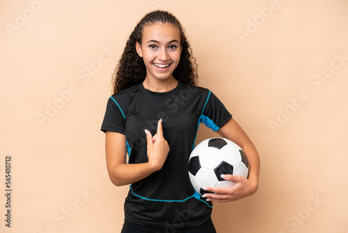 Young football player woman isolated on beige background with surprise facial expression © luismolinero
