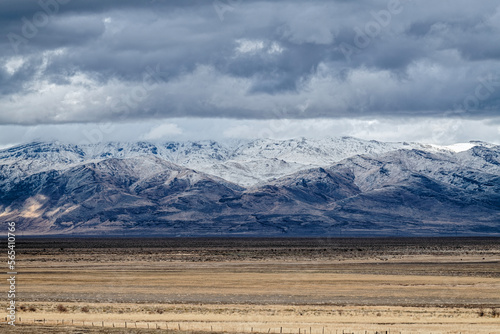 Canvas Print Layers of clouds hover over snow-capped mountains and fallow farm fields near Mi