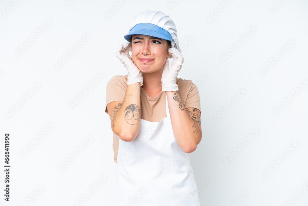 Fishmonger wearing an apron and holding a raw fish isolated on white background frustrated and covering ears Fishmonger wearing an apron and holding a raw fish isolated on white background frustrated and covering ears