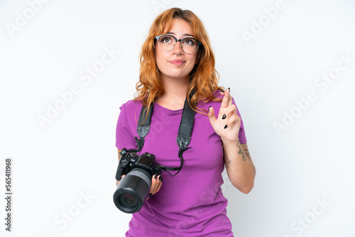 Young photographer caucasian woman isolated on white background with fingers crossing and wishing the best