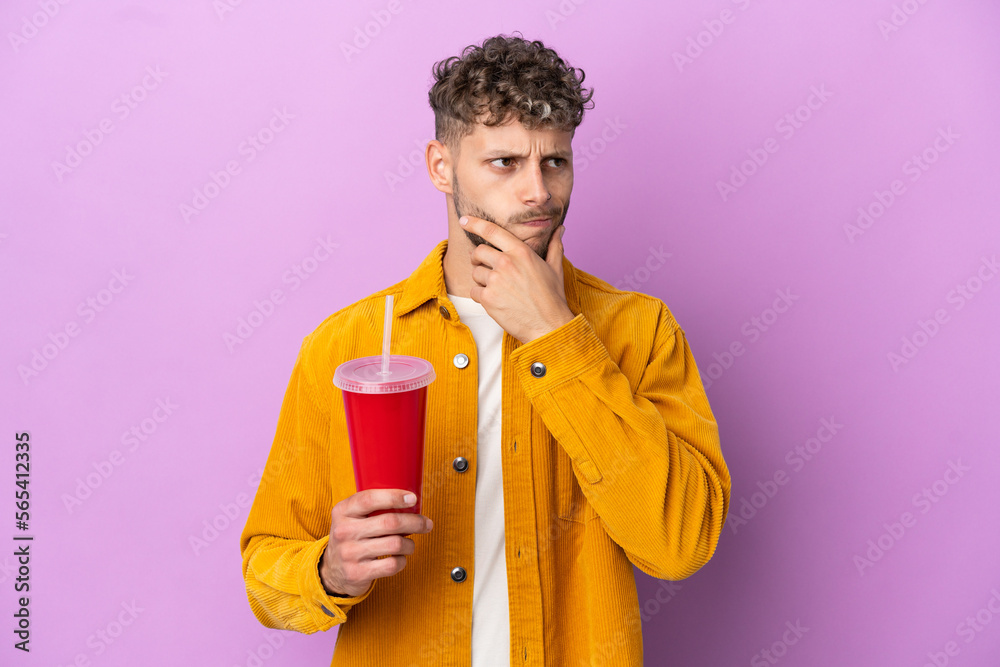 Young blonde man holding soda isolated on purple background having doubts and thinking Young blonde man holding soda isolated on purple background having doubts and thinking