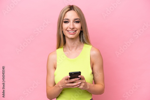Pretty blonde woman isolated on pink background sending a message with the mobile