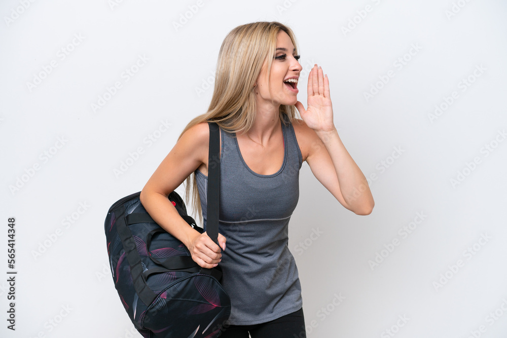 Young sport woman with sport bag isolated on white background shouting with mouth wide open to the lateral Young sport woman with sport bag isolated on white background shouting with mouth wide open to the lateral