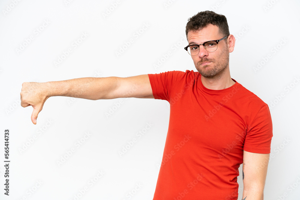 Young caucasian handsome man isolated on white background showing thumb down with negative expression Young caucasian handsome man isolated on white background showing thumb down with negative expression