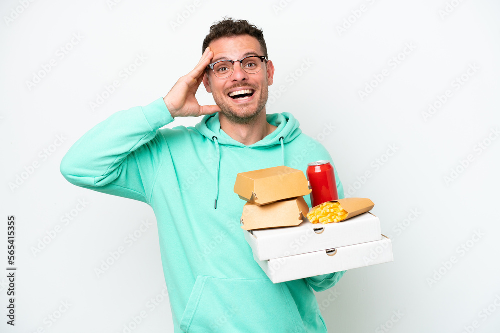 Young caucasian man holding fast food isolated on white background with surprise expression Young caucasian man holding fast food isolated on white background with surprise expression