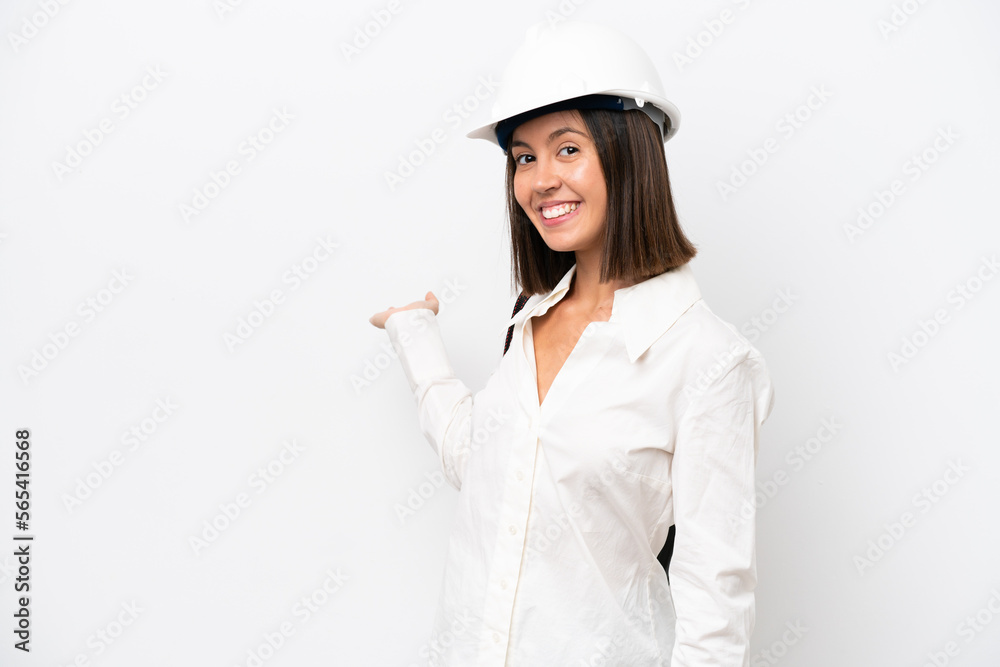 Young architect woman with helmet and holding blueprints isolated on white background extending hands to the side for inviting to come Young architect woman with helmet and holding blueprints isolated on white background extending hands to the side for inviting to come