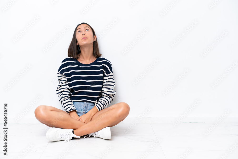 Young caucasian woman sitting on the floor isolated on white background and looking up Young caucasian woman sitting on the floor isolated on white background and looking up