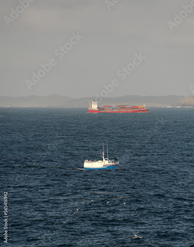 Cargo and fishing ships on a collision course in the blue sea