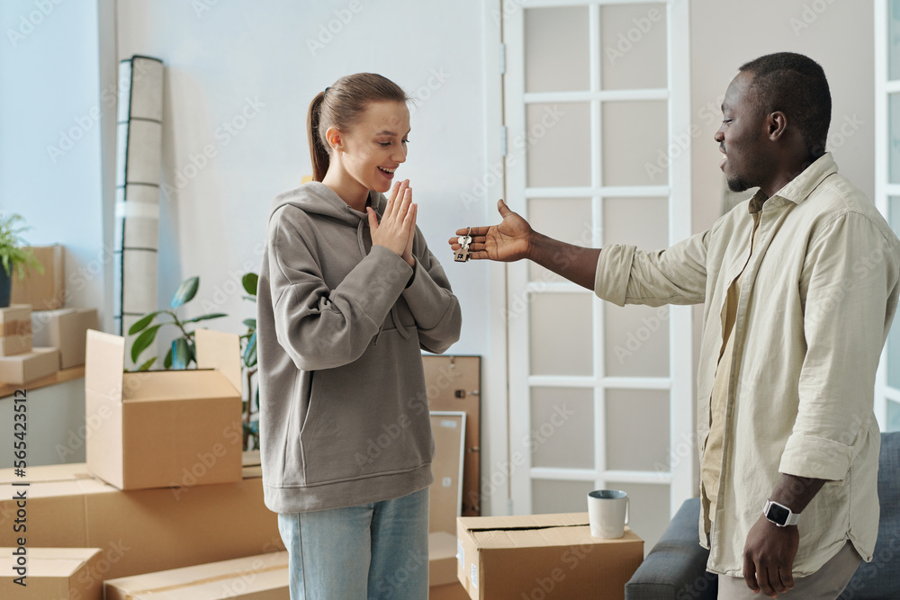 Happy girl getting keys from her new apartment from real estate agent, they standing in the room among packed boxes Happy girl getting keys from her new apartment from real estate agent, they standing in the room among packed boxes