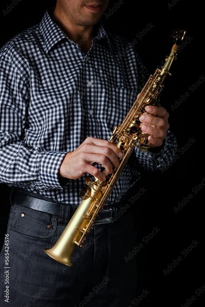 Naklejka premium soprano saxophone in hands on a black background