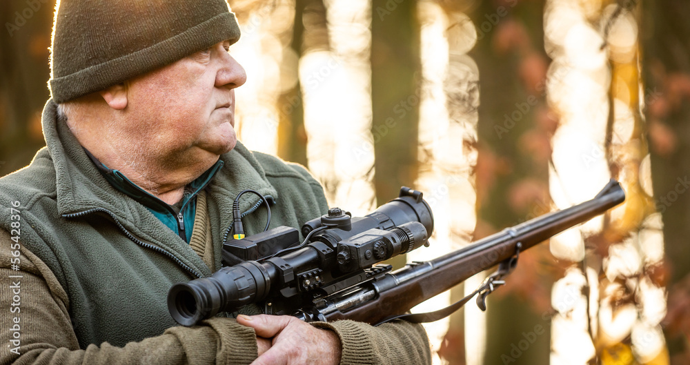 Fototapeta premium Portrait of hunter or ranger with a hunting gun and hunting form to hunt in an autumn forest, hunting concept
