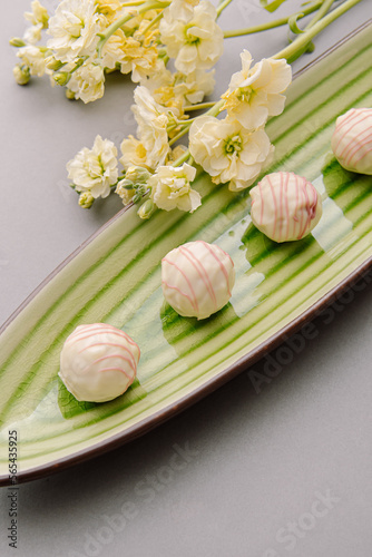 Tasty sweet truffles on green plate. Cheese truffles and flowers