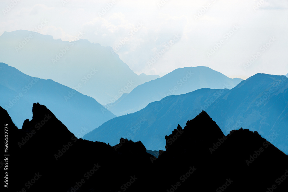 Spectacular blue and cyan mountain ranges silhouettes in early morning sunrise light. Alps, Vorarlberg, Austria.