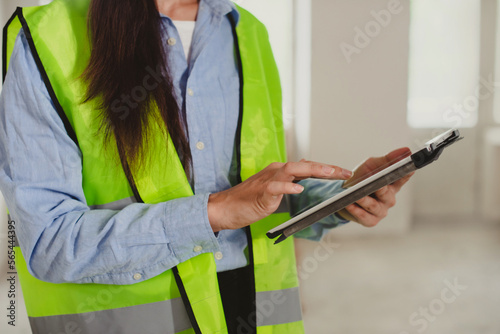 woman Industrial Engineer in High-Visibility Vest Working on Tablet Computer. Inspector or Safety Supervisor in construction site