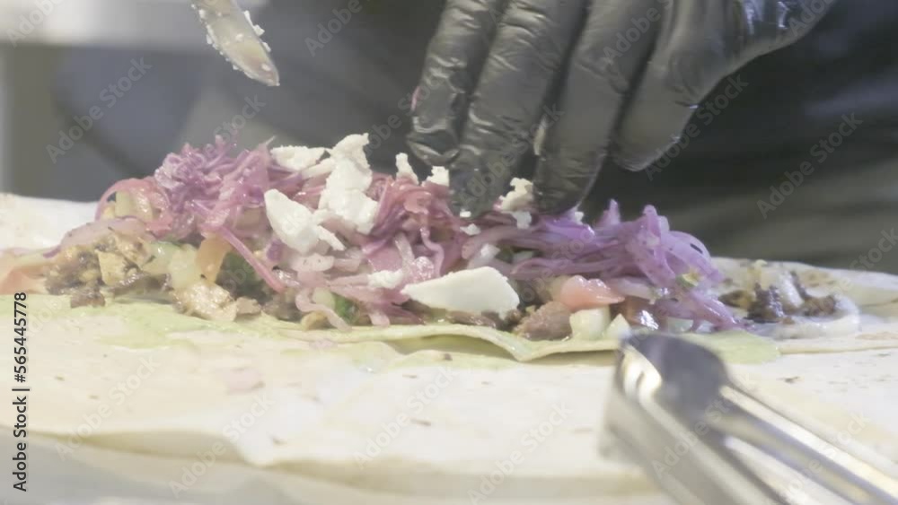 Cocinero preparando comida mediterranea, mexicana, oriental, con carne, pollo, cerdo envolviendo el pan árabe grabado en camara lenta