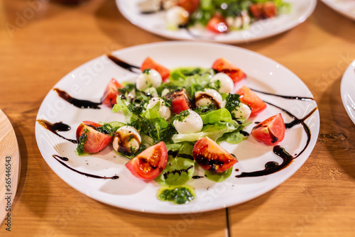 Plate of healthy classic close-up caprese salad with mozzarella cheese tomatoes and basil in kitchen - italian cuisine