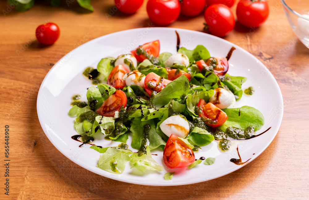 Plate of healthy classic close-up caprese salad with mozzarella cheese tomatoes and basil in kitchen - italian cuisine Plate of healthy classic close-up caprese salad with mozzarella cheese tomatoes and basil in kitchen - italian cuisine