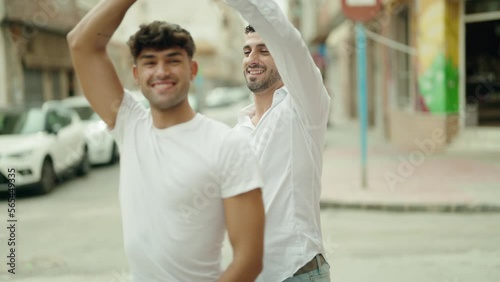 Two hispanic men couple smiling confident dancing at street