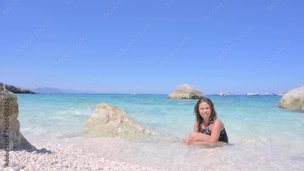 Little girl on the beach plays in the waves. Pure azure sea and sun glare. Happy moment for a child. High quality FullHD footage Little girl on the beach plays in the waves. Pure azure sea and sun glare. Happy moment for a child. High quality FullHD footage