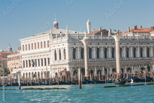 VENICE, ITALY - FEBRAURY 14, 2020: View on St. Marco square from water with Library, coloumns of St. Marco and St. Theodor, boats and gondolas on water.