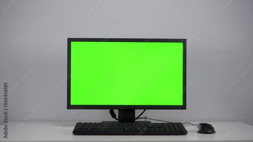 Turning on the monitor with a green screen. A man with his hand turns on the computer screen on the desktop in the office. Chroma key. Turning on the monitor with a green screen. A man with his hand turns on the computer screen on the desktop in the office. Chroma key.