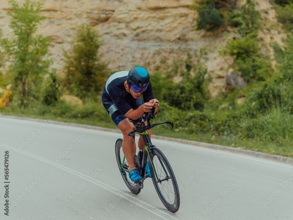 Full length portrait of an active triathlete in sportswear and with a protective helmet riding a bicycle. Selective focus Full length portrait of an active triathlete in sportswear and with a protective helmet riding a bicycle. Selective focus