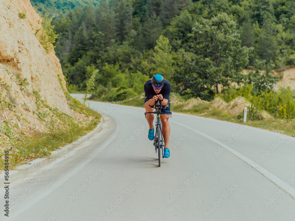 Obraz premium Full length portrait of an active triathlete in sportswear and with a protective helmet riding a bicycle. Selective focus 