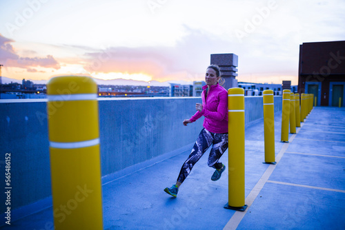Full length of determined sportswoman running through bollards on terrace during sunset