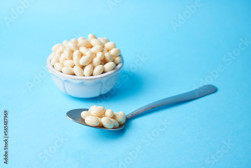 Probiotic and lactobacillus supplement pills on a bowl with a blue background