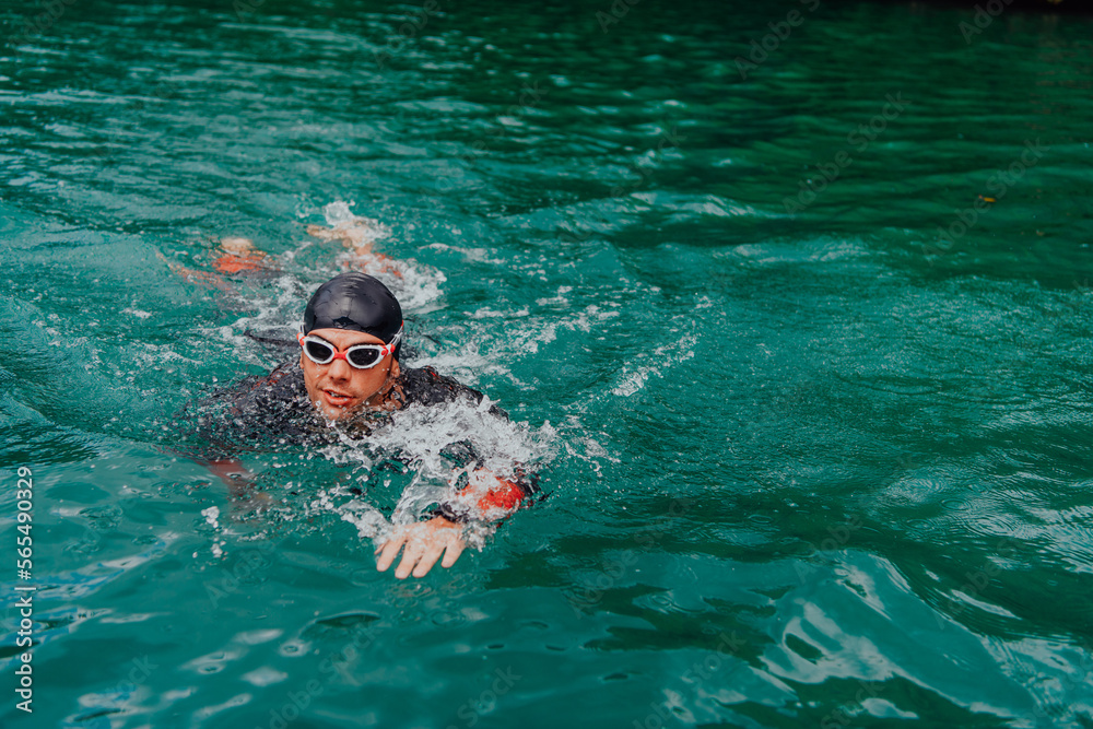 A triathlete in a professional swimming suit trains on the river while preparing for Olympic swimming