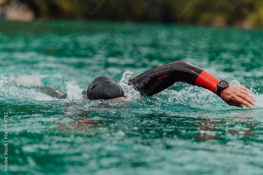 A triathlete in a professional swimming suit trains on the river while preparing for Olympic swimming