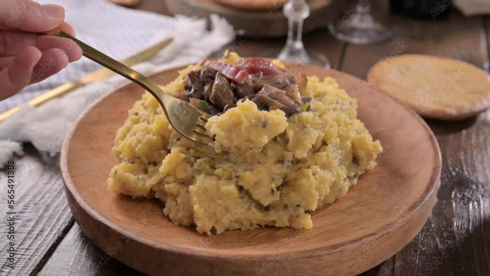 polenta with porcini mushrooms, bacon, served on a dark wooden background. Typical food of northern Italy, Trentino in the Alps . 4k polenta with porcini mushrooms, bacon, served on a dark wooden background. Typical food of northern Italy, Trentino in the Alps . 4k