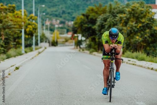 Fototapeta Naklejka Na Ścianę i Meble -  Full length portrait of an active triathlete in sportswear and with a protective helmet riding a bicycle. Selective focus 
