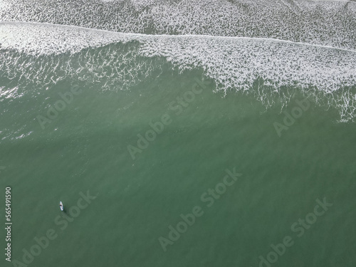 aerial view of ocean waves and paddle boarder