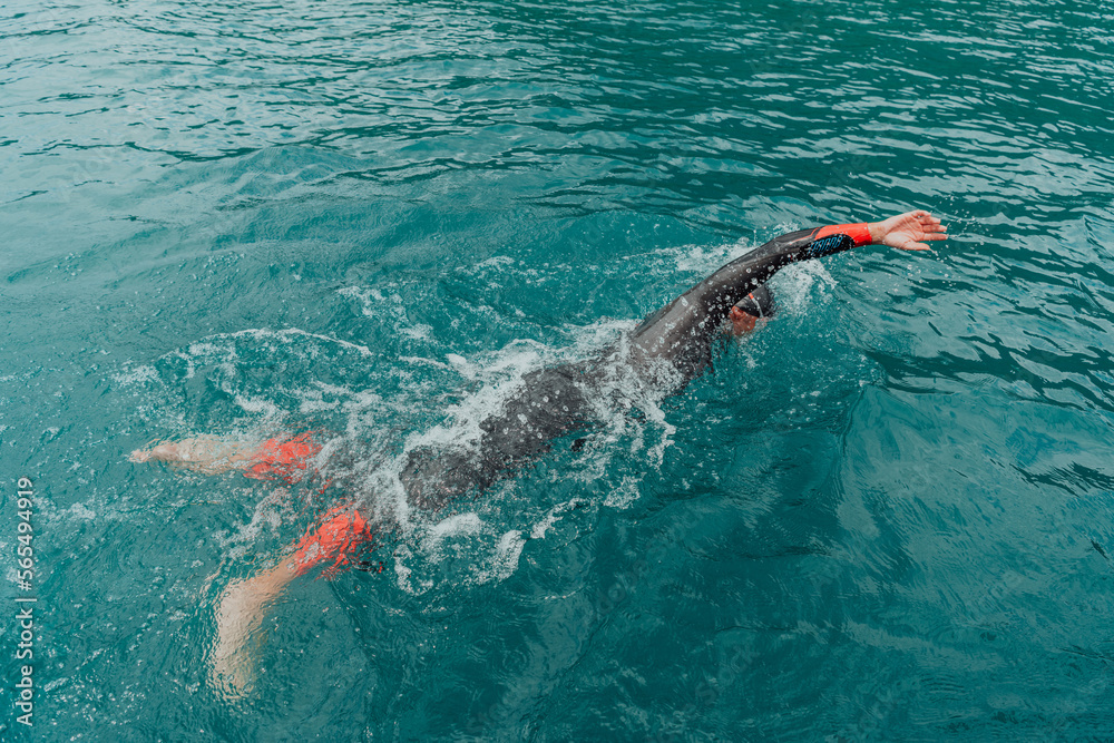 A triathlete in a professional swimming suit trains on the river while preparing for Olympic swimming