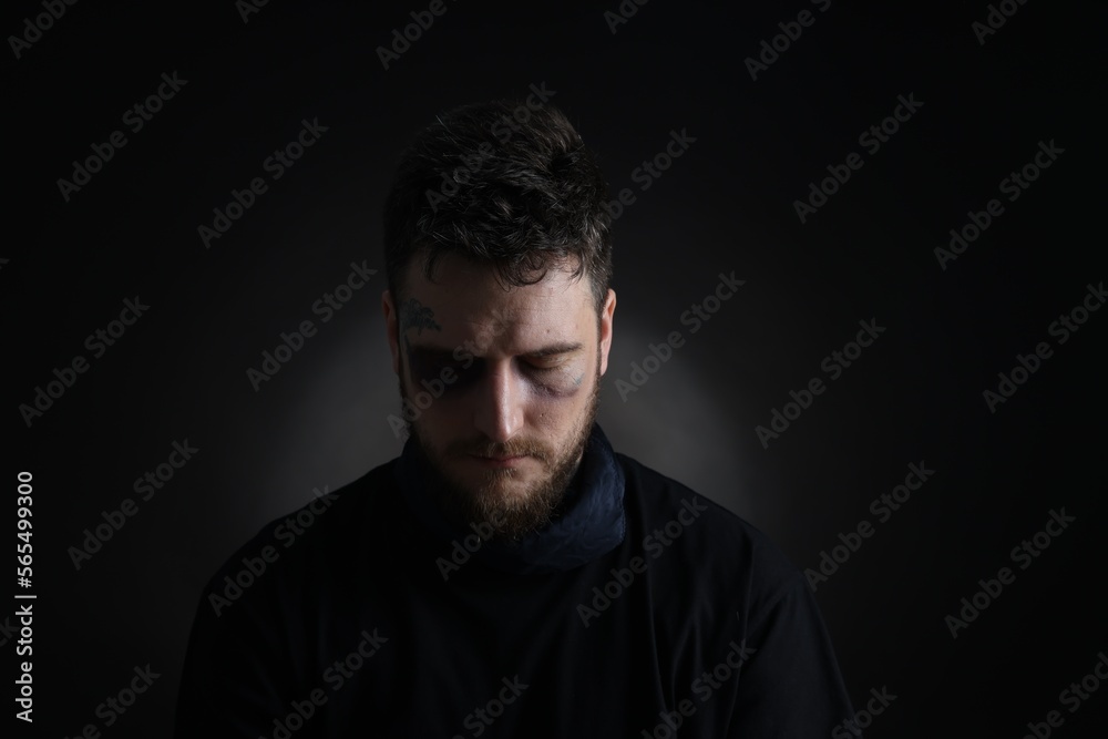 Man with bruise on dark background. Hostage