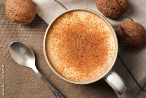 Delicious eggnog with cinnamon and walnuts on wooden table, flat lay. Space for text