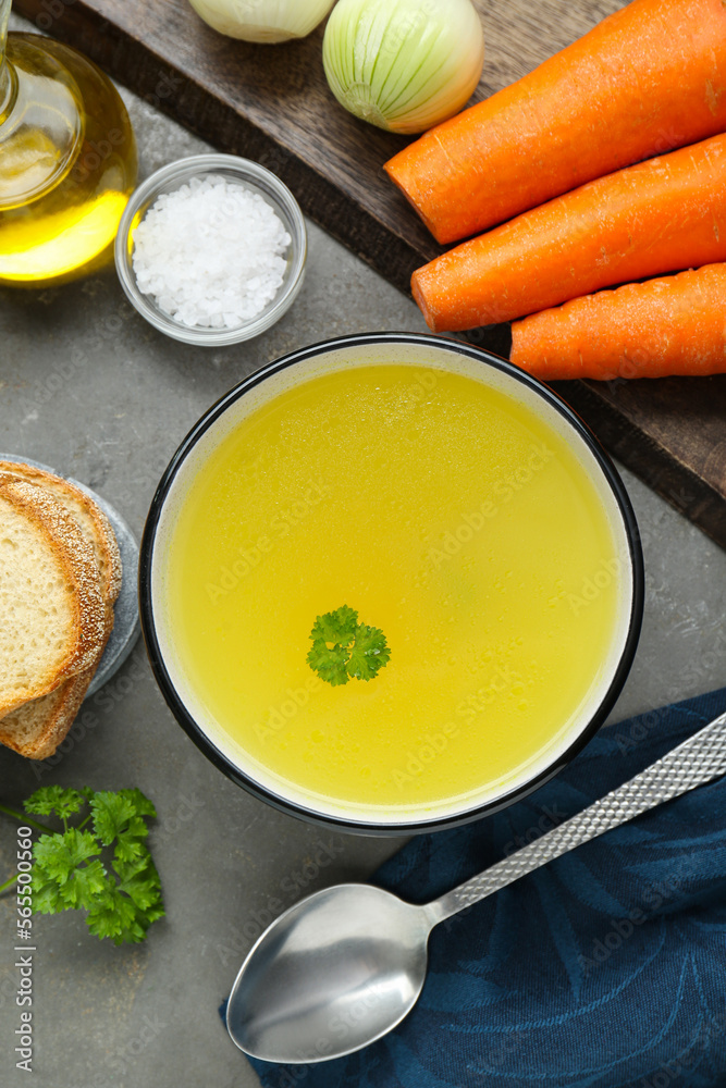 Delicious chicken bouillon and ingredients on grey table, flat lay Delicious chicken bouillon and ingredients on grey table, flat lay