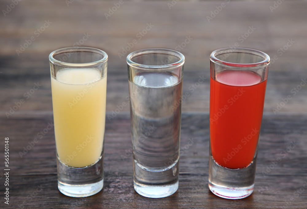 Shots with lime juice, tequila and sangria as colors of mexican flag on wooden table, closeup. Traditional serving Shots with lime juice, tequila and sangria as colors of mexican flag on wooden table, closeup. Traditional serving