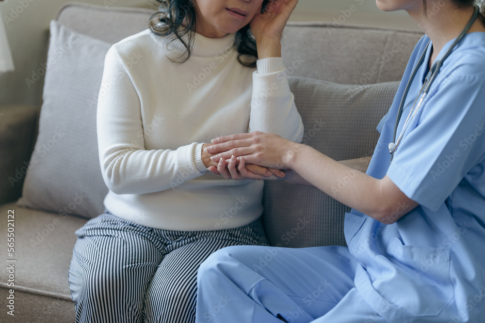 Fototapeta premium Portrait of attractive young caucasian female nurse elderly caregivers with senior patient home caring for elderly asia female patients on couch, indoors. hand clasp to encourage