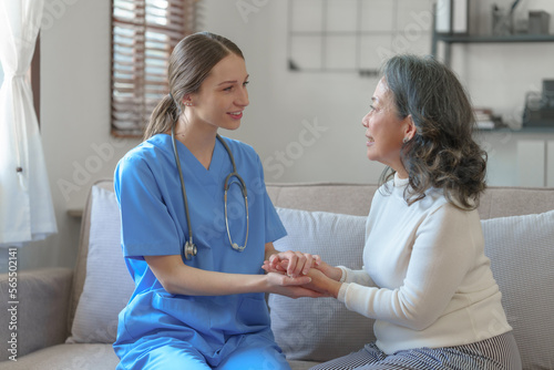 Portrait of attractive young caucasian female nurse elderly caregivers with senior patient home caring for elderly asia female patients on couch, indoors. hand clasp to encourage