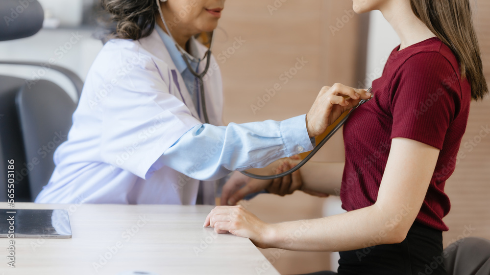 Female elder doctor takes a history of a patient and gives a consultation about osteopathy to a female patient after measuring blood pressure and heart rate and encouragement by holding hands Female elder doctor takes a history of a patient and gives a consultation about osteopathy to a female patient after measuring blood pressure and heart rate and encouragement by holding hands