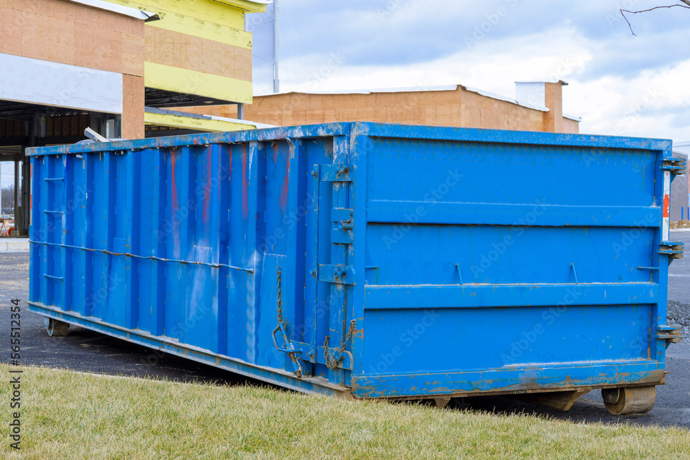blue dumpster, bin near new construction site of apartment houses building blue dumpster, bin near new construction site of apartment houses building