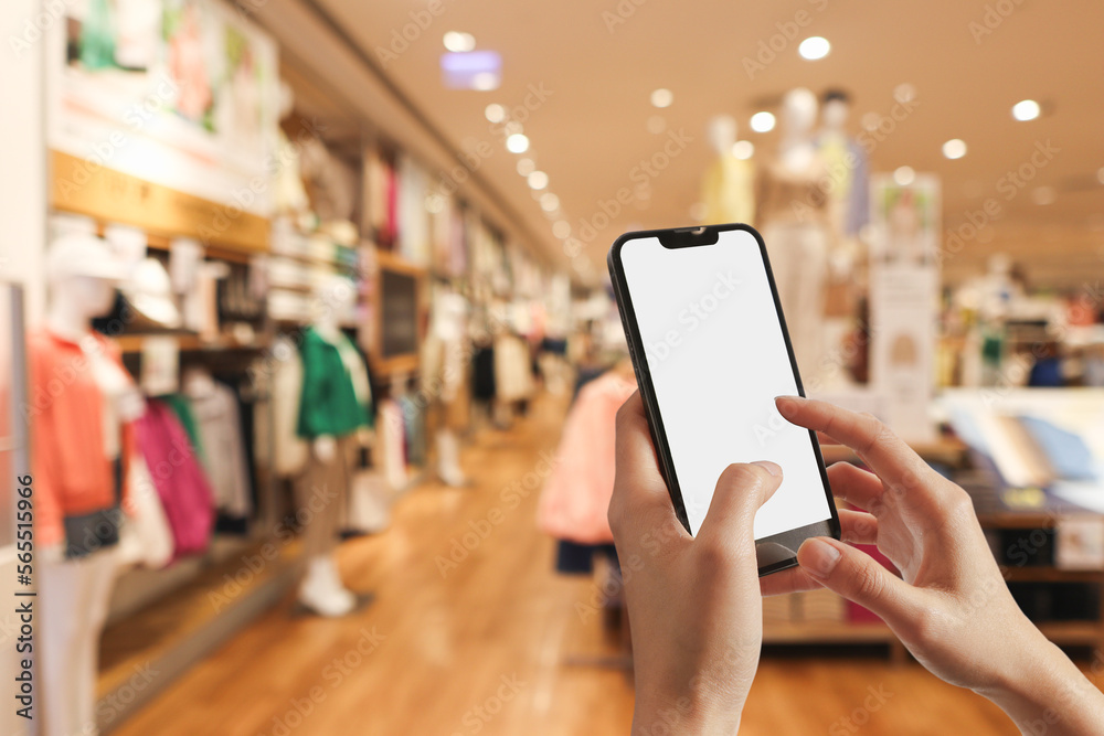 Woman holding mobile phone pressing payment for online shopping against blurred background of department stores. Online shopping concepts.