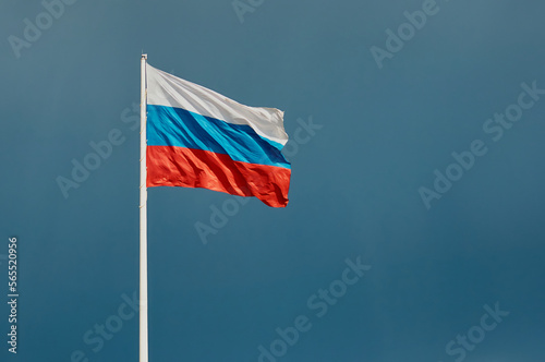Russian flag against a dark blue sky with empty space for text. The state flag of the Russian Federation, 75 meters high, flutters in the wind. Built-in anemometer and emergency flag lowering system.