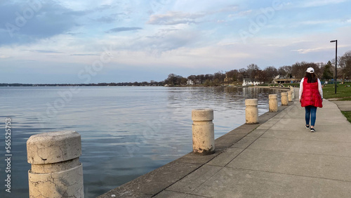 woman walk lakefront path at sunset
